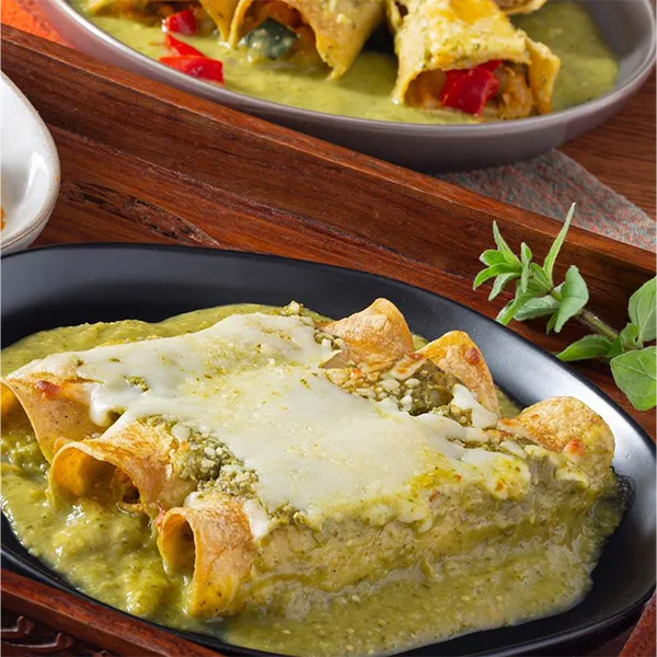 Mexican enchiladas with green salsa and melted cheese prepared for Latin meal delivery.