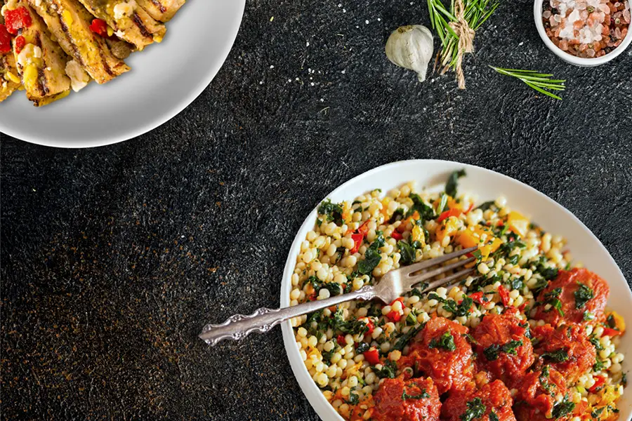 Mediterranean chicken and couscous bowl with vegetables and herbs served on plates