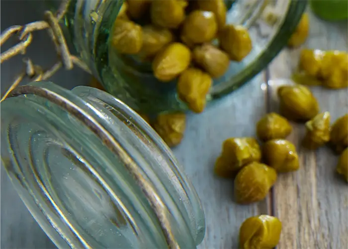 Capers spilling from a glass jar, Mediterranean gourmet ingredient used in healthy and flavorful cooking