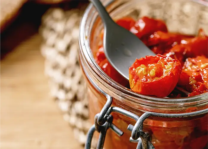 Sun-dried tomatoes in a glass jar with olive oil, Mediterranean healthy ingredients for cooking