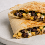 Cross-section of a black bean and corn quesadilla showing melted Monterey Jack and Cotija cheese filling with black beans, corn, and jalapeño