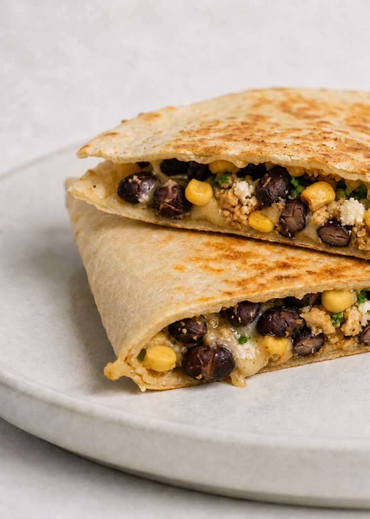 Cross-section of a black bean and corn quesadilla showing melted Monterey Jack and Cotija cheese filling with black beans, corn, and jalapeño