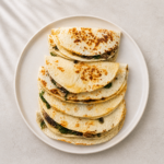 Stacked Mushroom and Spinach Quesadillas on a white plate, pre-grilled flour tortillas filled with mushrooms, spinach, and Monterey Jack cheese