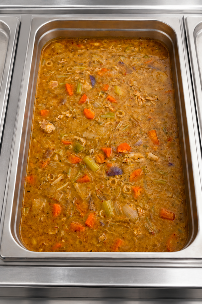 Demeter's Pantry Pollo Guisado Puerto Rican chicken stew with carrots, potatoes, and olives in a hot bar tray