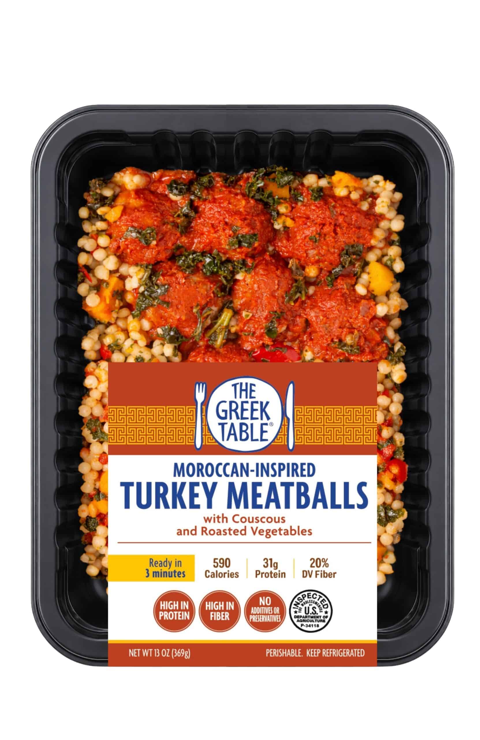 Moroccan-inspired turkey meatballs with couscous and roasted vegetables in a black tray.