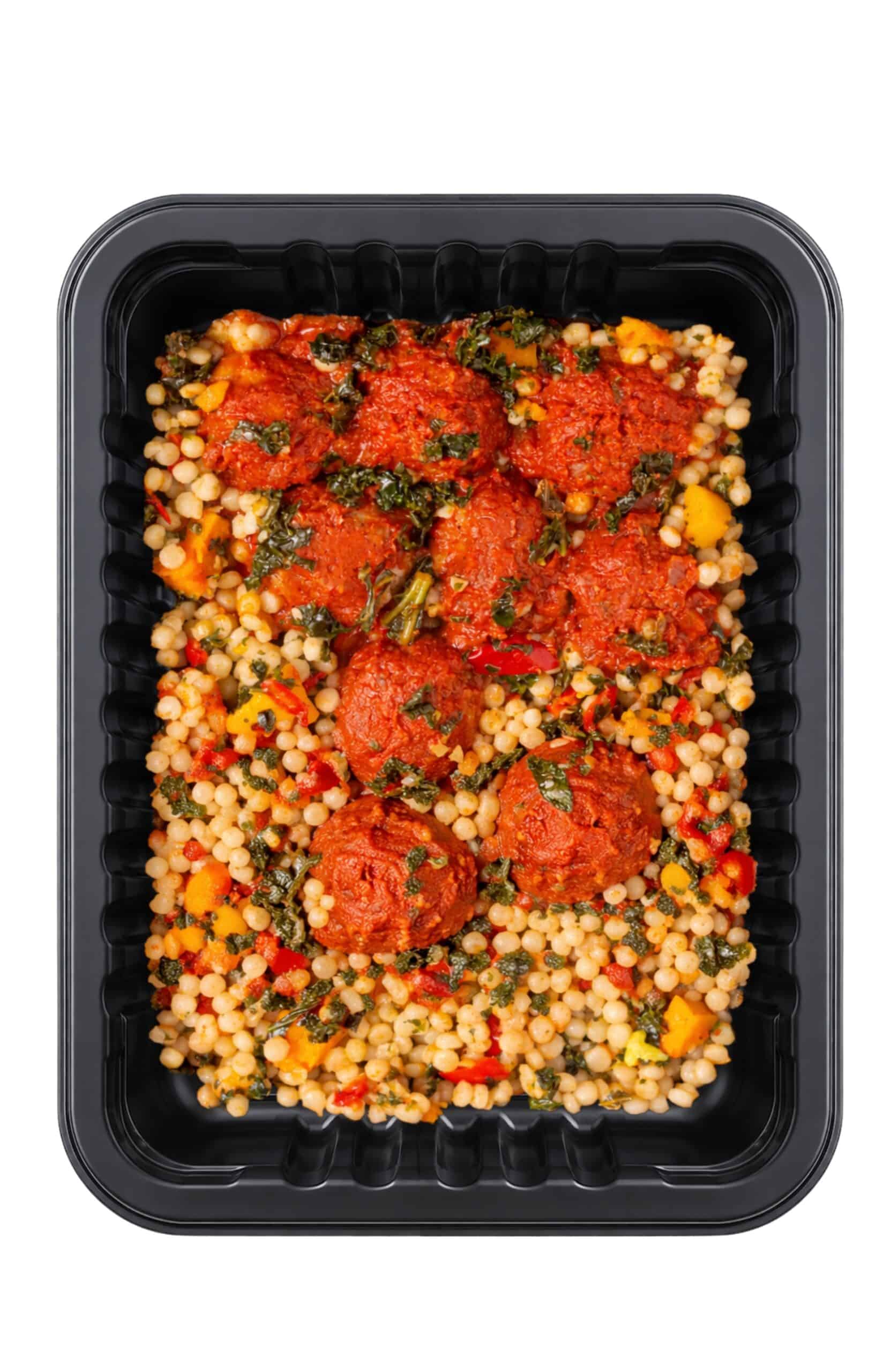 Moroccan-inspired turkey meatballs with couscous and roasted vegetables in a black tray.