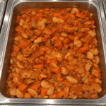 Close-up of a hearty bean and vegetable stew in a stainless steel tray. Demeter's Pantry Mediterranean White Bean Stew in Hot Bar Pan